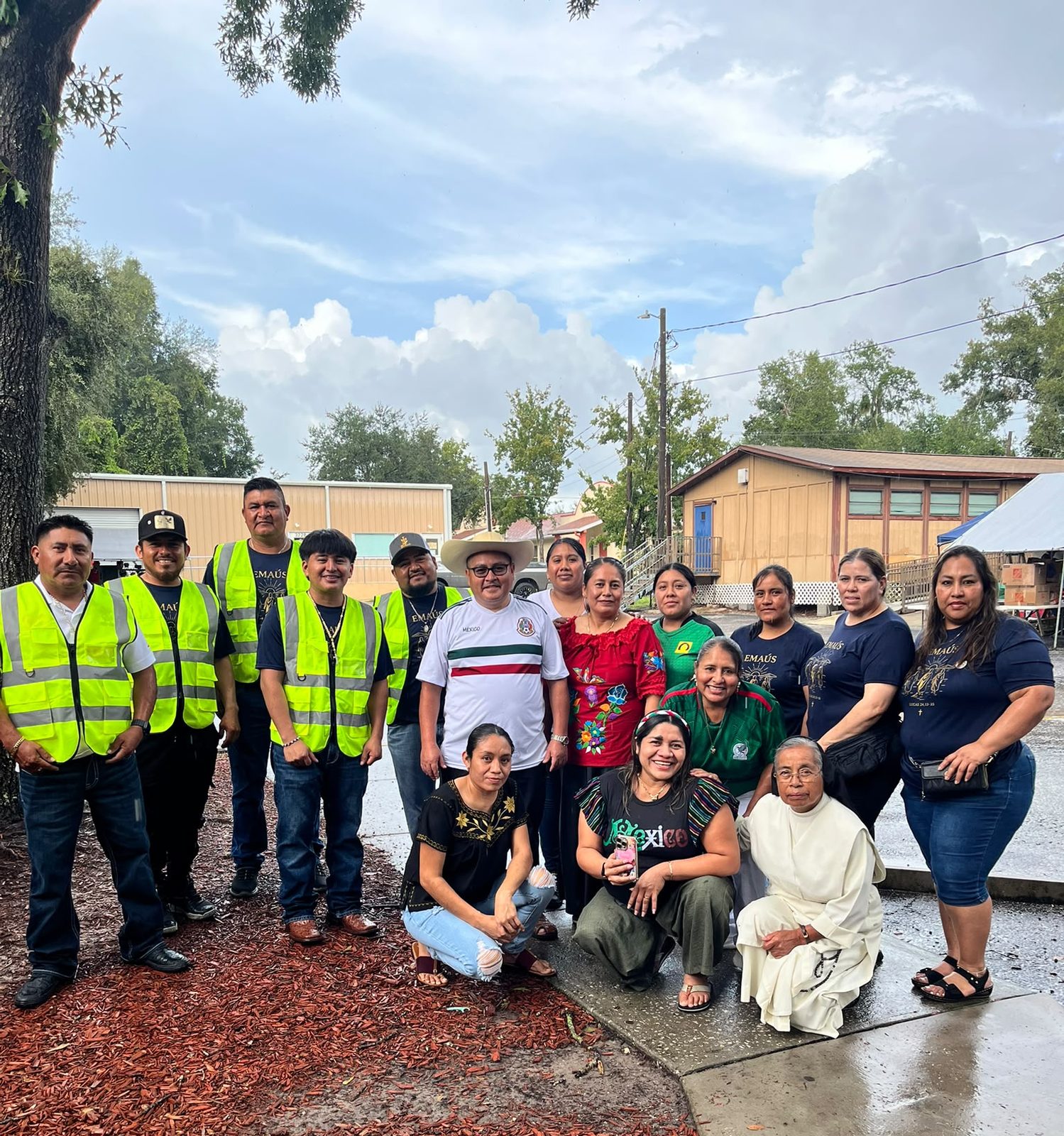 Members of the Emmaus group in reflective vests with a Dominican sister, in front of the Mission