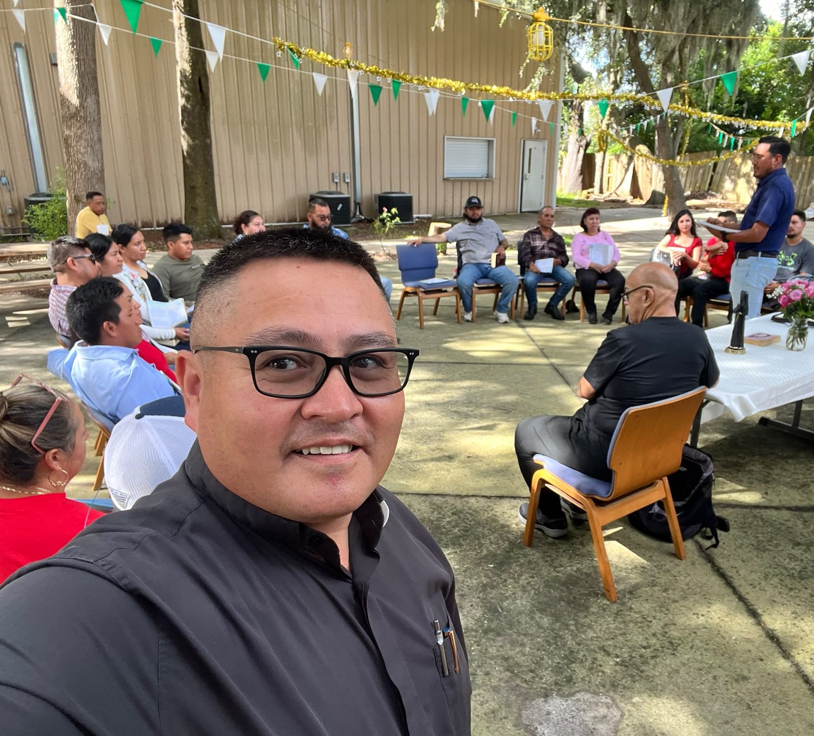 Circle gathering in the Mission courtyard, decorated with green and white pennants